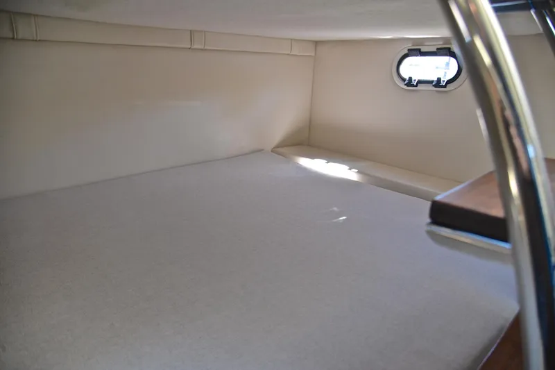 Slide: The Image of 2016 Regal 26 Express cabin interior with a small window and cushioned bed. - 33