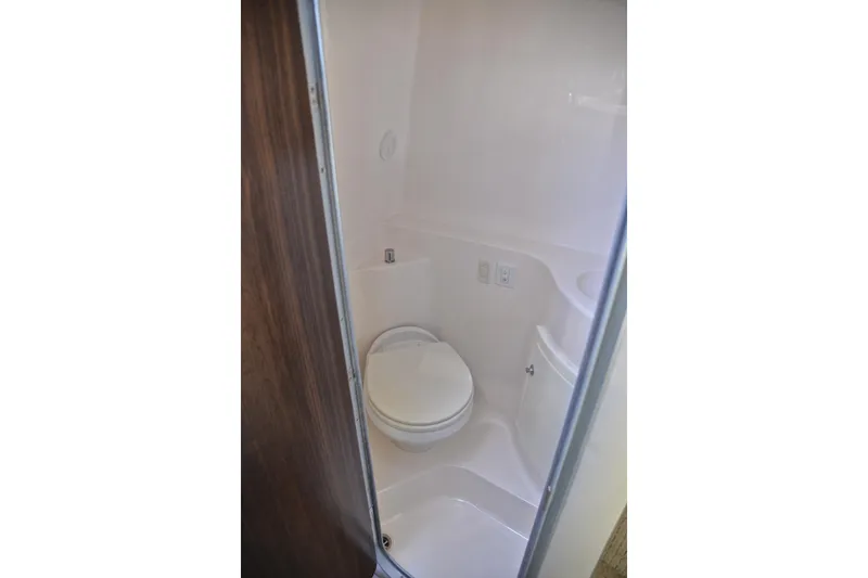 Slide: The Image of Compact bathroom in 2016 Regal 26 Express boat, featuring a white toilet and sleek design. - 42