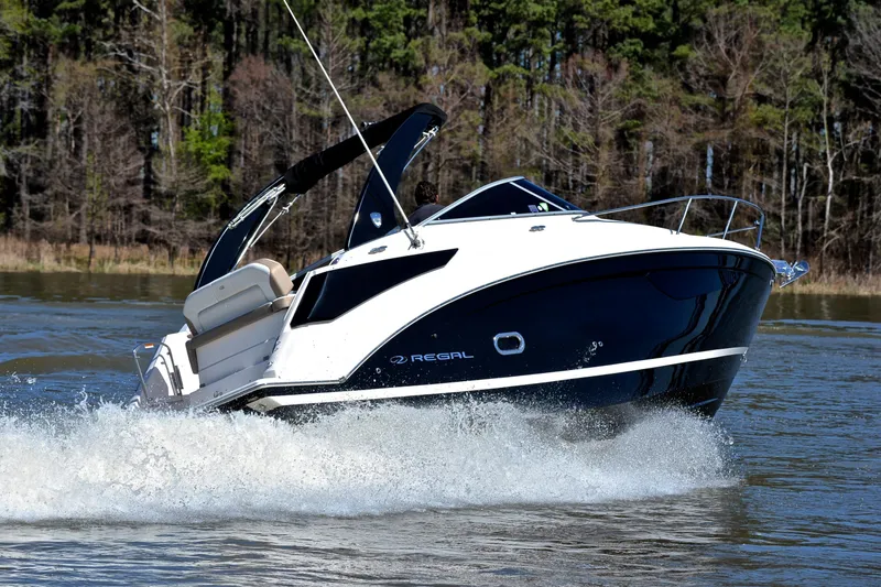 Slide: The Image of 2016 Regal 26 Express boat cruising on a lake with forested background. - 5