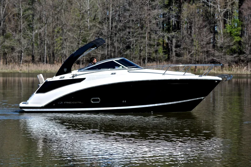 Slide: The Image of 2016 Regal 26 Express boat cruising on a calm lake with forest backdrop. - 8