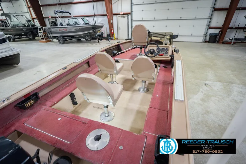 Slide: The Image of 1997 Lund 1650 Angler SS boat interior with red carpet and beige seats in a showroom. - 13