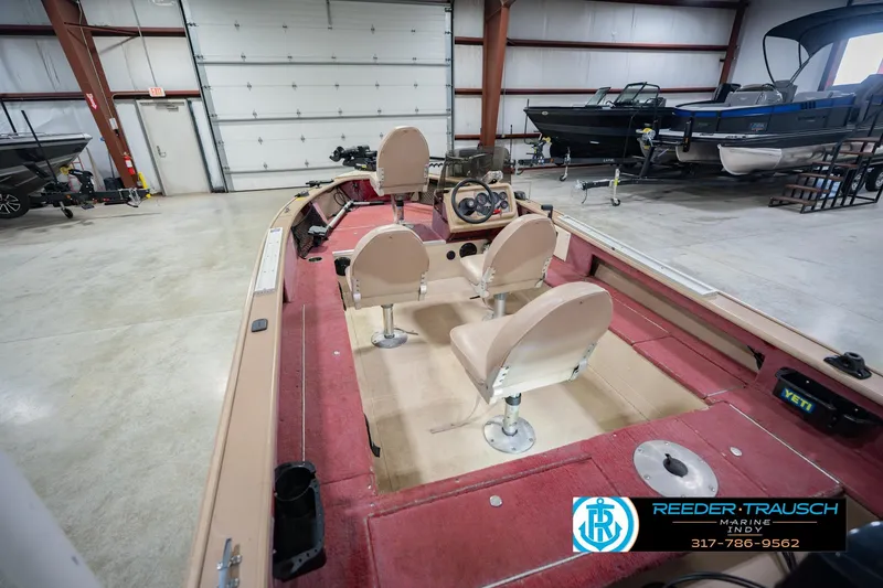 Slide: The Image of 1997 Lund 1650 Angler SS boat interior with red carpet and beige seats in a showroom. - 14