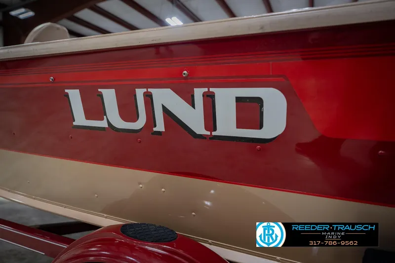 Slide: The Image of Red and beige 1997 Lund 1650 Angler SS boat with logo in a showroom. - 50
