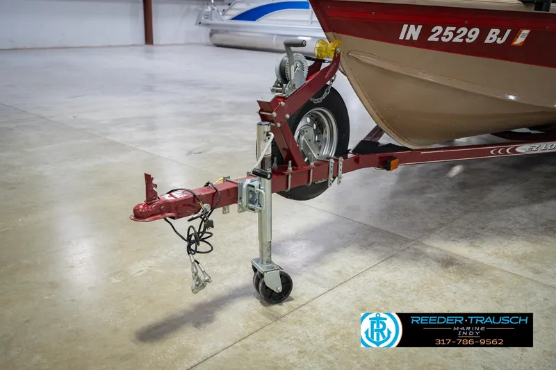 Slide: The Image of 1997 Lund 1650 Angler SS boat trailer with hitch and wheel in a showroom. - 52
