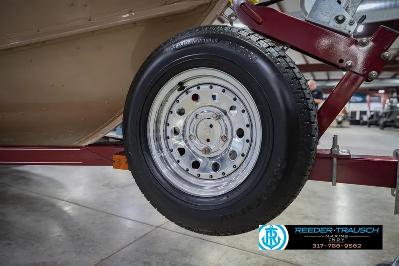 Slide: The Image of Trailer wheel of a 1997 Lund 1650 Angler SS boat in a showroom. - 54