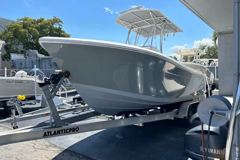 The Image of 2019 Cobia 220 Center Console boat on trailer, parked outdoors under clear blue sky. - 0