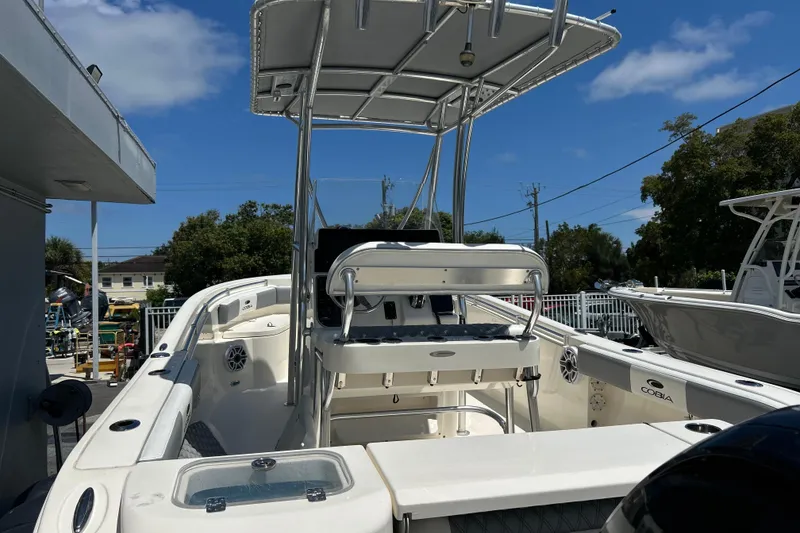 Slide: The Image of 2019 Cobia 220 Center Console boat with T-top, docked under clear blue sky. - 17