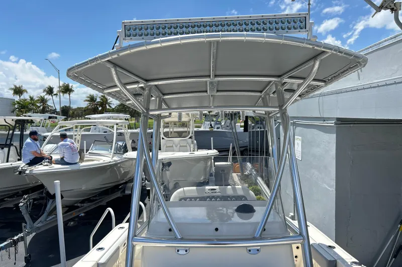 Slide: The Image of 2019 Cobia 220 Center Console boat with T-top, docked under clear blue sky. - 18