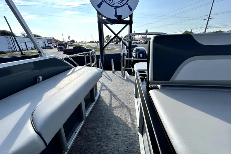 Slide: The Image of 2025 Godfrey Sweetwater 2286 SFL pontoon boat interior with seating and helm, docked under sunny skies. - 46