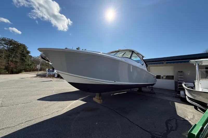The Image of 2022 Pursuit DC 326 Dual Console boat displayed outdoors under a clear blue sky. - 2