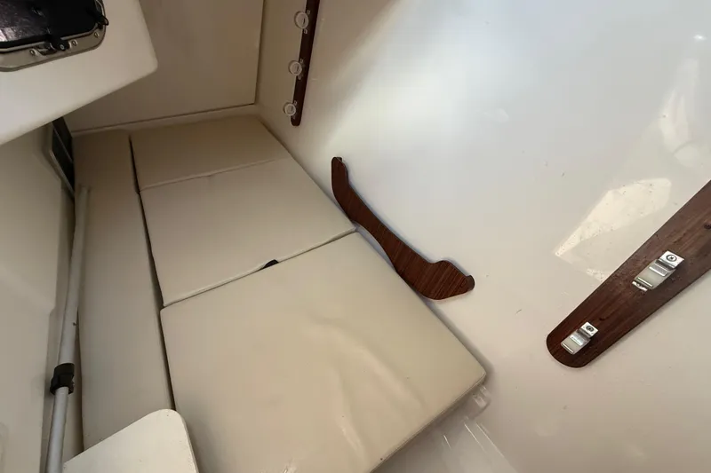 Slide: The Image of 2022 Pursuit DC 326 Dual Console interior cabin with cushioned seating and wooden accents. - 20