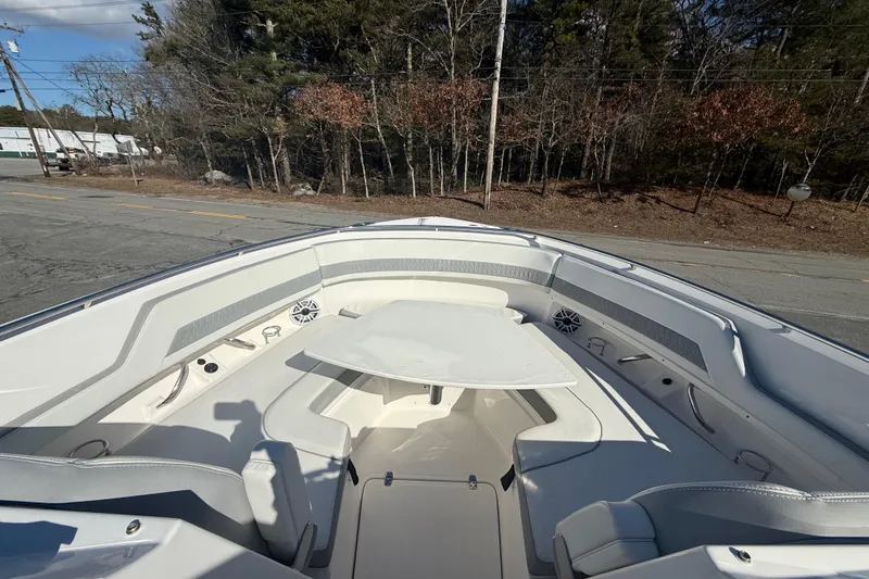 Slide: The Image of 2022 Pursuit DC 326 Dual Console boat interior with seating and table, parked on roadside. - 21