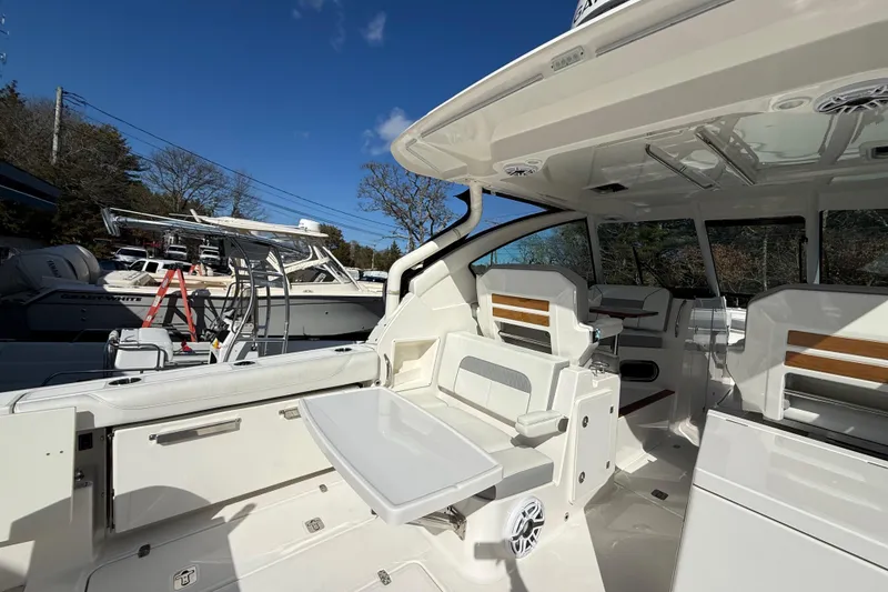 Slide: The Image of 2022 Pursuit DC 326 Dual Console boat interior with seating and table under clear blue sky. - 8