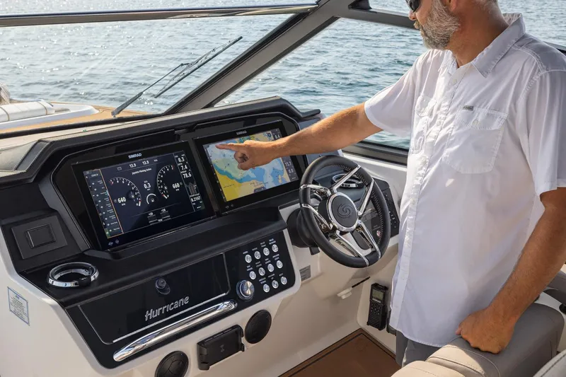 Slide: The Image of Man operating 2026 Hurricane SunDeck 3200 OB boat dashboard with navigation screens. - 11