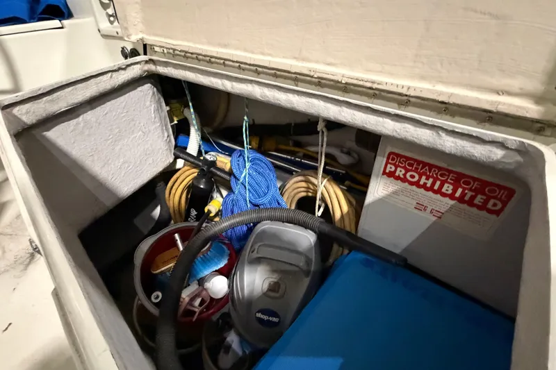 Slide: The Image of Storage compartment on a 1985 C&C 35 MK III sailboat with equipment and "Discharge of Oil Prohibited" sign. - 11