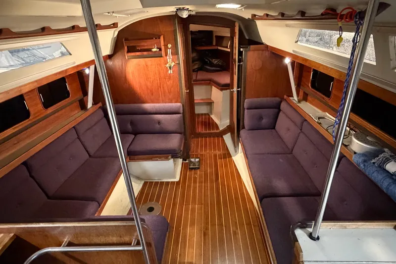 Slide: The Image of Interior of 1985 C&C 35 MK III sailboat with wood paneling and purple seating. - 13
