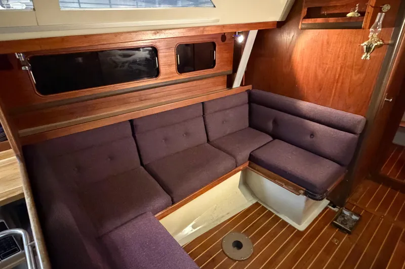 Slide: The Image of Interior of 1985 C&C 35 MK III sailboat with purple cushioned seating and wooden paneling. - 14