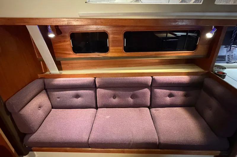 Slide: The Image of 1985 C&C 35 MK III yacht interior with purple cushioned seating and wooden accents. - 16