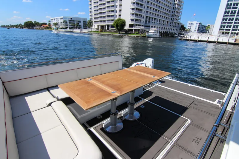 Slide: The Image of 2021 Jeanneau Leader 12.5 WA yacht with elegant seating and table, docked by waterfront buildings. - 30