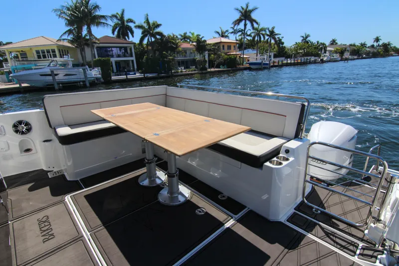 Slide: The Image of 2021 Jeanneau Leader 12.5 WA boat with outdoor seating and table, docked by waterfront homes. - 32