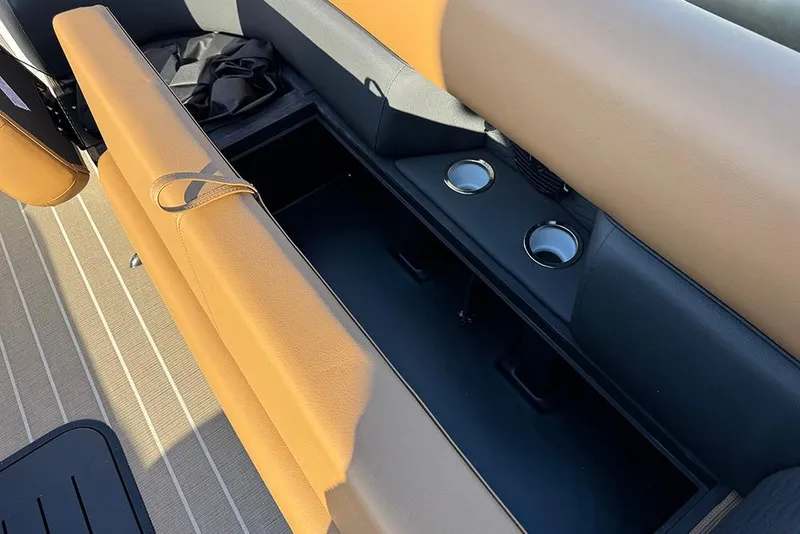 Slide: The Image of 2026 Bentley Pontoons Elite 253 Admiral interior storage with cup holders and tan seating. - 21