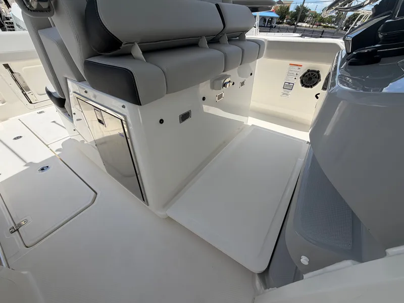 Slide: The Image of The image shows the interior of a Boston Whaler 330 Outrage with gray upholstery and storage space. - 29
