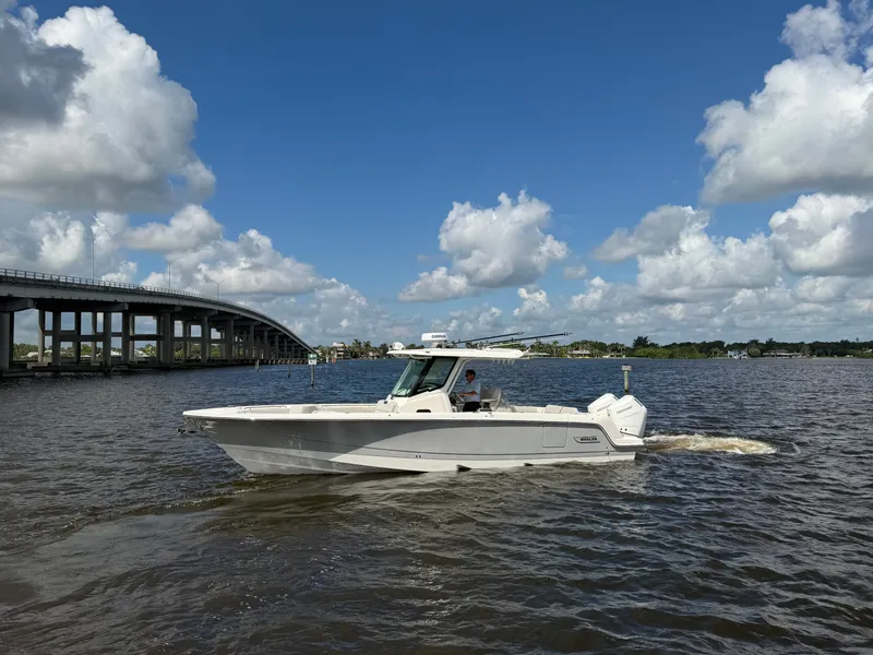 Slide: The Image of A 2026 Boston Whaler 330 Outrage cruising on a river under a cloudy sky. - 1