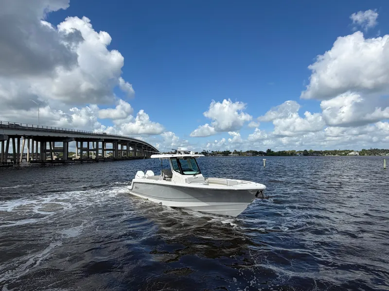 Slide: The Image of 2026 Boston Whaler 330 Outrage on a river under blue skies with a bridge in the background. - 11