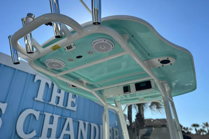 Slide: The Image of 2020 Everglades 243 Center Console boat with speakers and rod holders, under clear blue sky. - 12