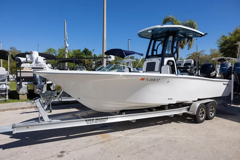 The Image of 2025 Tidewater 2500 Carolina Bay boat on trailer, parked outdoors under clear blue sky. - 1