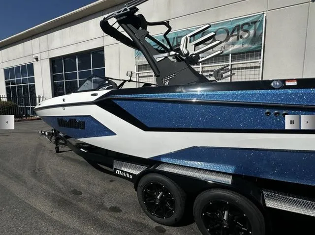 Slide: The Image of 2025 Malibu Wakesetter 23 MXZ boat in blue and white outside a building. - 3