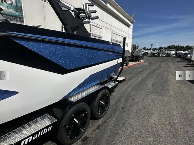 Slide: The Image of 2025 Malibu Wakesetter 23 MXZ boat on trailer, blue and white design. - 4