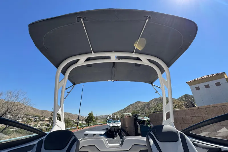 Slide: The Image of 2019 Yamaha Boats 212 Limited S with bimini top, scenic mountain backdrop. - 17