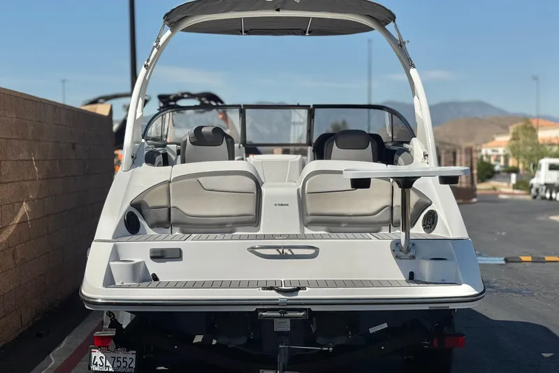 Slide: The Image of 2019 Yamaha Boats 212 Limited S, rear view with seating and table, parked outdoors. - 4