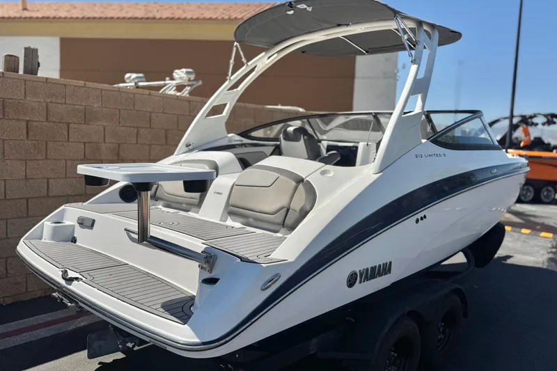 Slide: The Image of 2019 Yamaha Boats 212 Limited S, sleek white design, rear view with seating and table. - 5