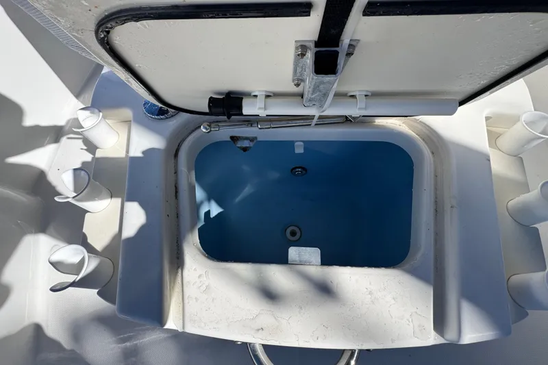 Slide: The Image of Open storage compartment on 2012 Boston Whaler 200 Dauntless boat, featuring rod holders. - 17