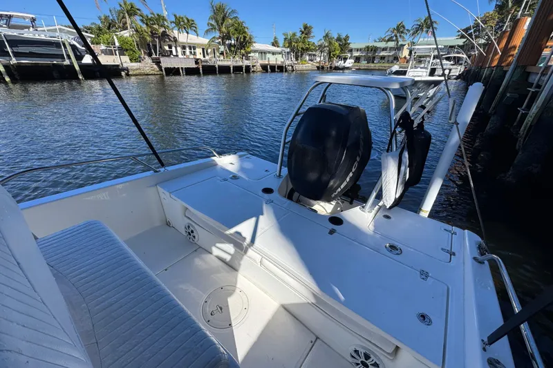 Slide: The Image of 2012 Boston Whaler 200 Dauntless boat interior with seating and Mercury engine, docked by waterfront. - 4