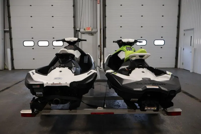 Slide: The Image of Two 2023 Sea-Doo Spark 3up jet skis on a trailer in a garage. - 2