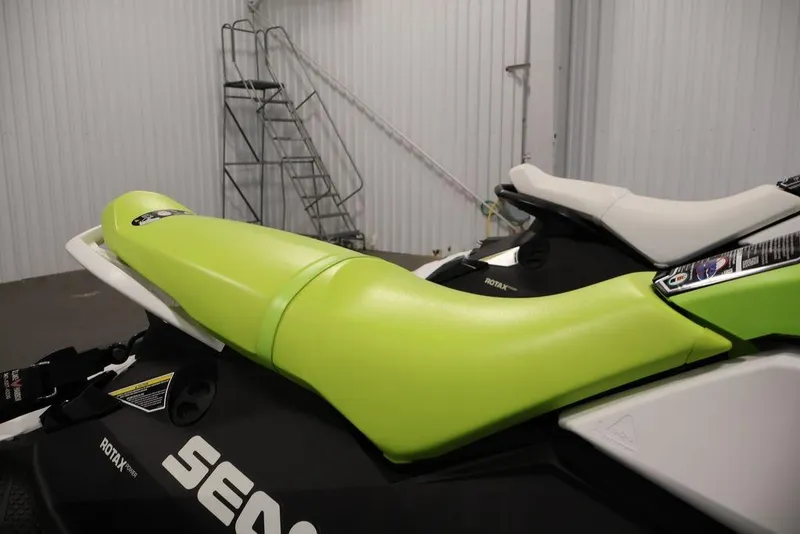 Slide: The Image of 2023 Sea-Doo Spark 3up jet ski with vibrant green seat in a garage setting. - 23