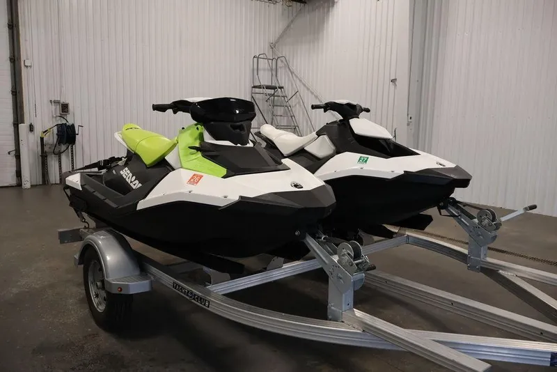 Slide: The Image of 2023 Sea-Doo Spark 3up jet skis on trailer in garage setting. - 3