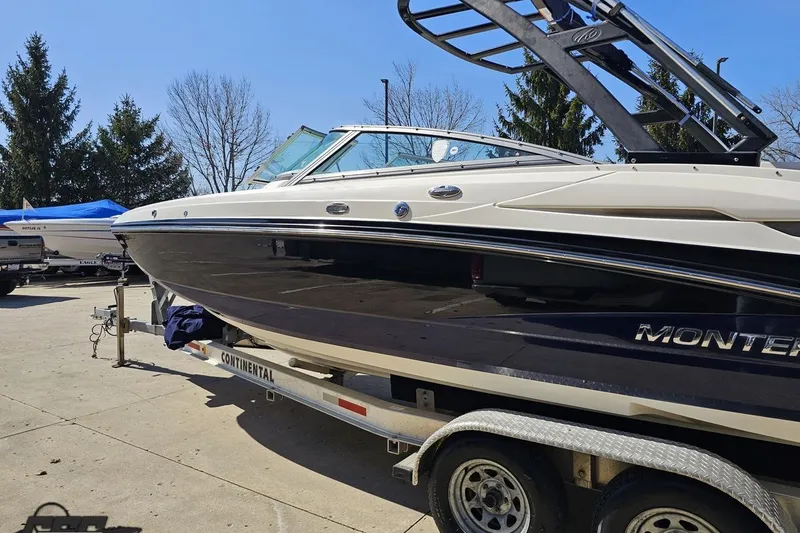 Slide: The Image of 2013 Monterey M3 Sport Boat on trailer, parked outdoors under clear blue sky. - 23