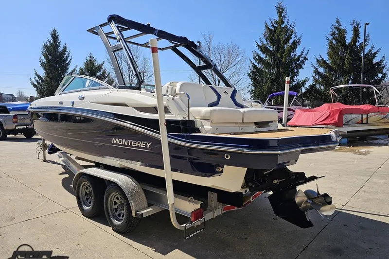 Slide: The Image of 2013 Monterey M3 Sport Boat on trailer, parked outdoors, with trees in the background. - 25