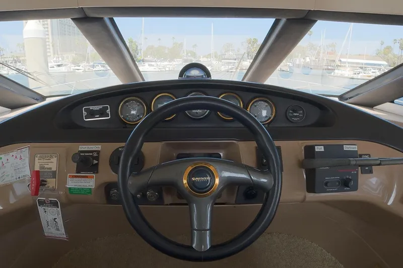 Slide: The Image of 1999 Carver 53 Voyager helm with steering wheel and instrument panel in marina setting. - 15