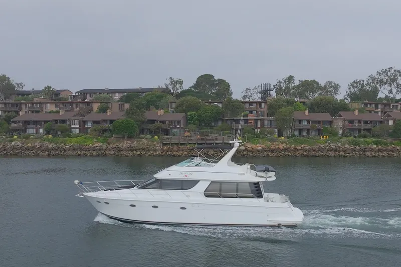 Slide: The Image of 1999 Carver 53 Voyager yacht cruising near waterfront homes. - 30