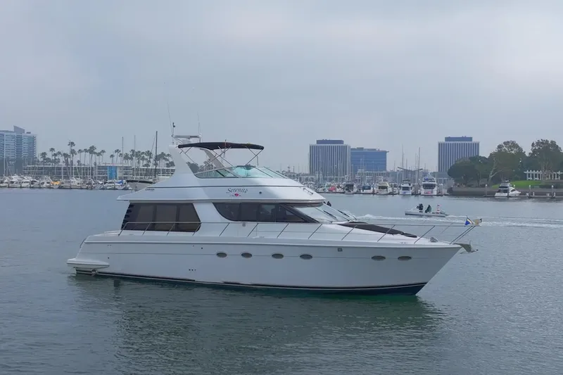 Slide: The Image of 1999 Carver 53 Voyager yacht cruising in a marina with cityscape background. - 4