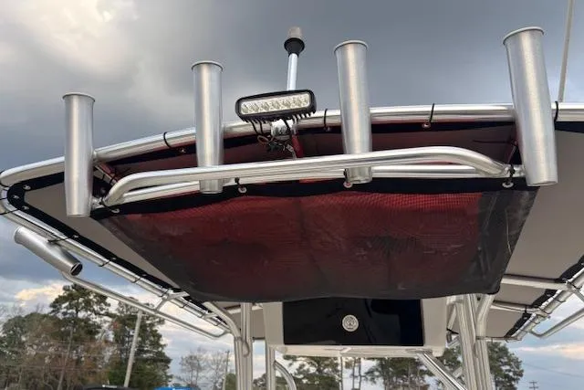 Slide: The Image of 2024 Carolina Skiff 25 LS boat with rod holders and canopy under cloudy sky. - 28