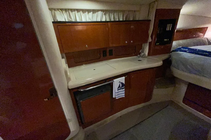 Slide: The Image of Interior of 2002 Sea Ray Sundancer 320 yacht, featuring a compact kitchenette and cozy sleeping area. - 24