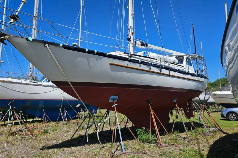 Slide: The Image of 1989 Pacific Seacraft 37 sailboat docked on a calm river with lush greenery. - 3