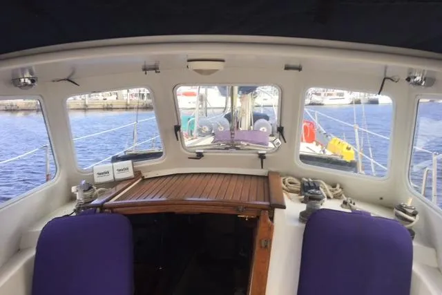 Slide: The Image of 1989 Pacific Seacraft 37 sailboat cockpit with purple seats and marina view. - 44