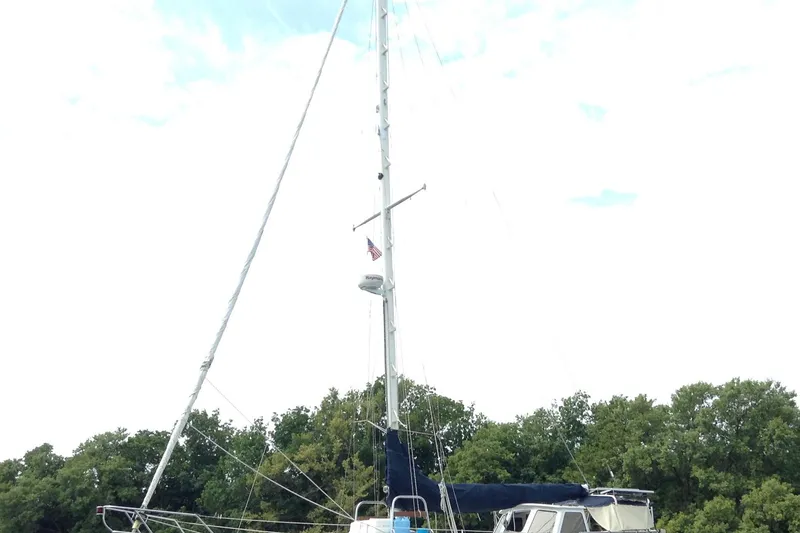 Slide: The Image of 1989 Pacific Seacraft 37 sailboat with tall mast, docked near lush green trees. - 52